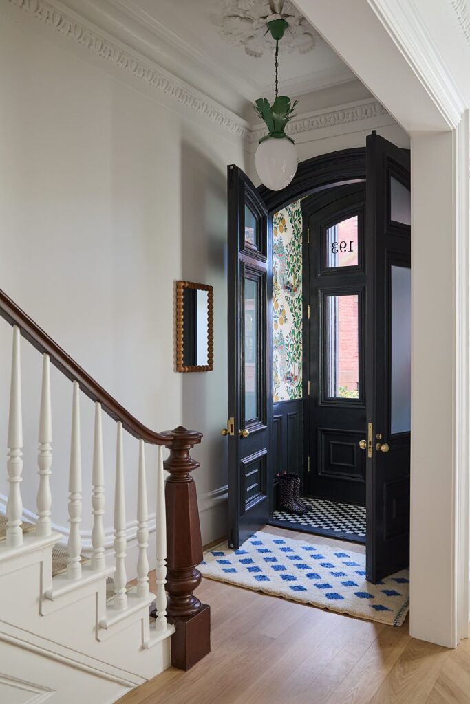 Entryway of a Brooklyn brownstone — black double doors, original moldings, and a runner rug. Renovated by Twin Fork Interiors.